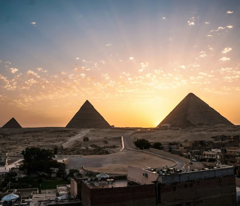 Panoramic sunset view over the Giza pyramid complex from a rooftop vantage point - Pyramids Cairo tour