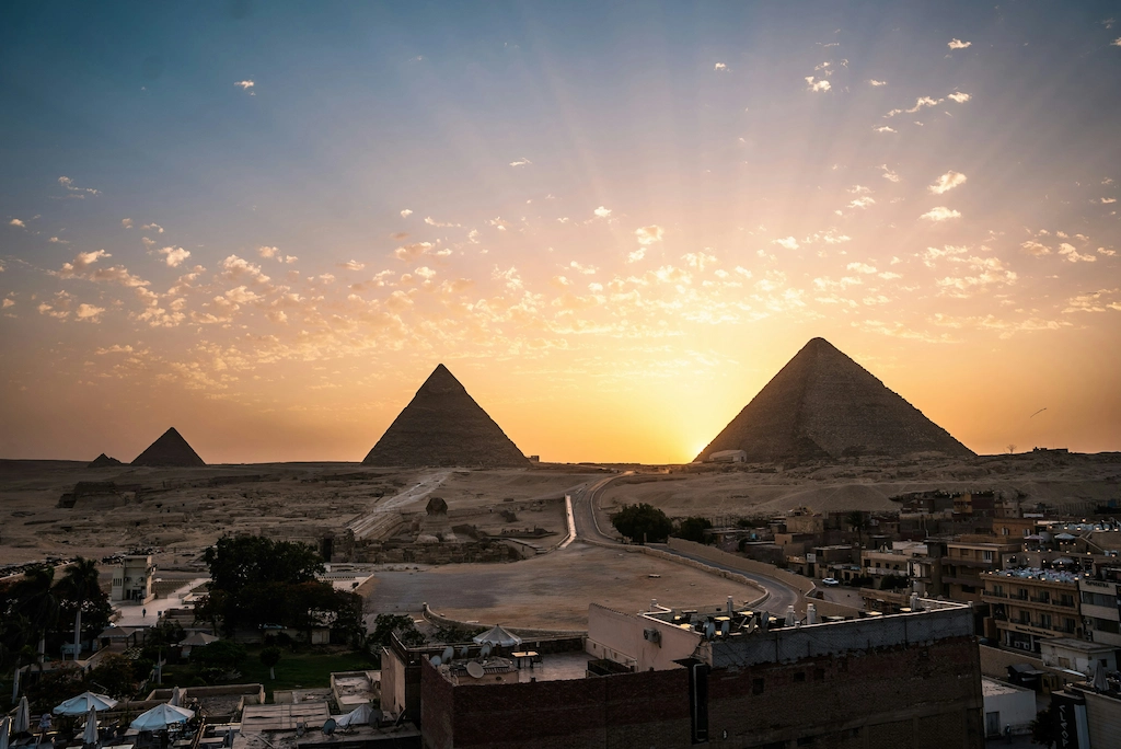 Panoramic sunset view over the Giza pyramid complex from a rooftop vantage point - Pyramids Cairo tour