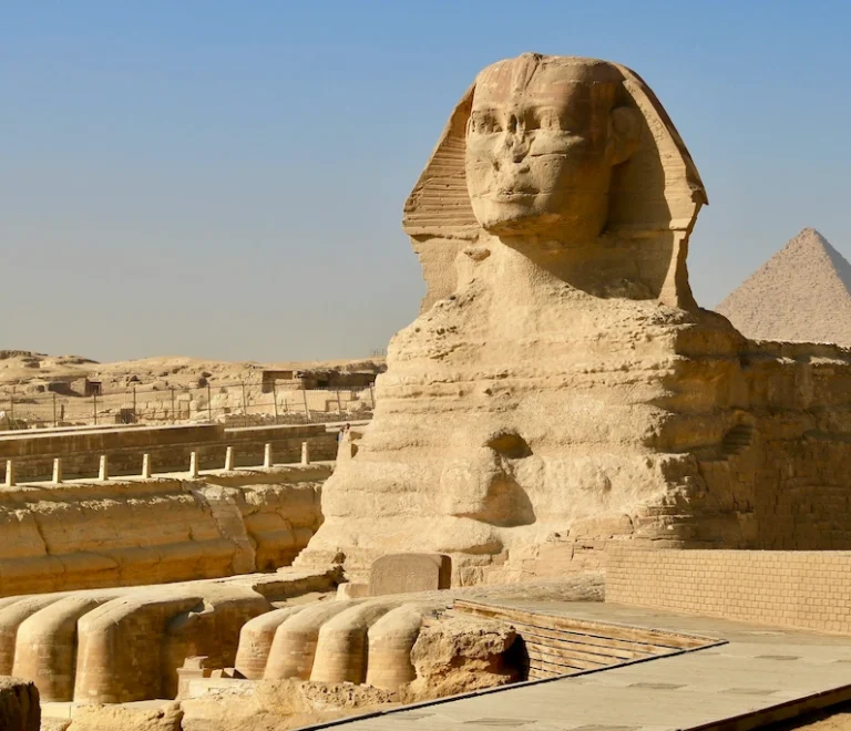 Close-up profile view of the Great Sphinx of Giza with the pyramid in the background - Pyramids Cairo tour
