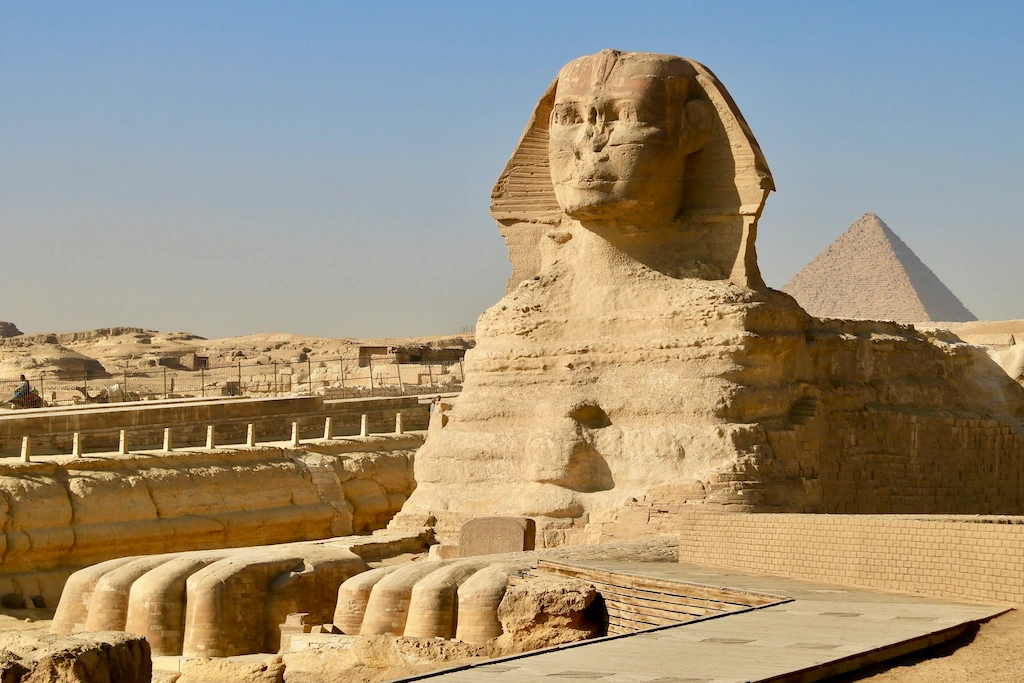 Close-up profile view of the Great Sphinx of Giza with the pyramid in the background - Pyramids Cairo tour