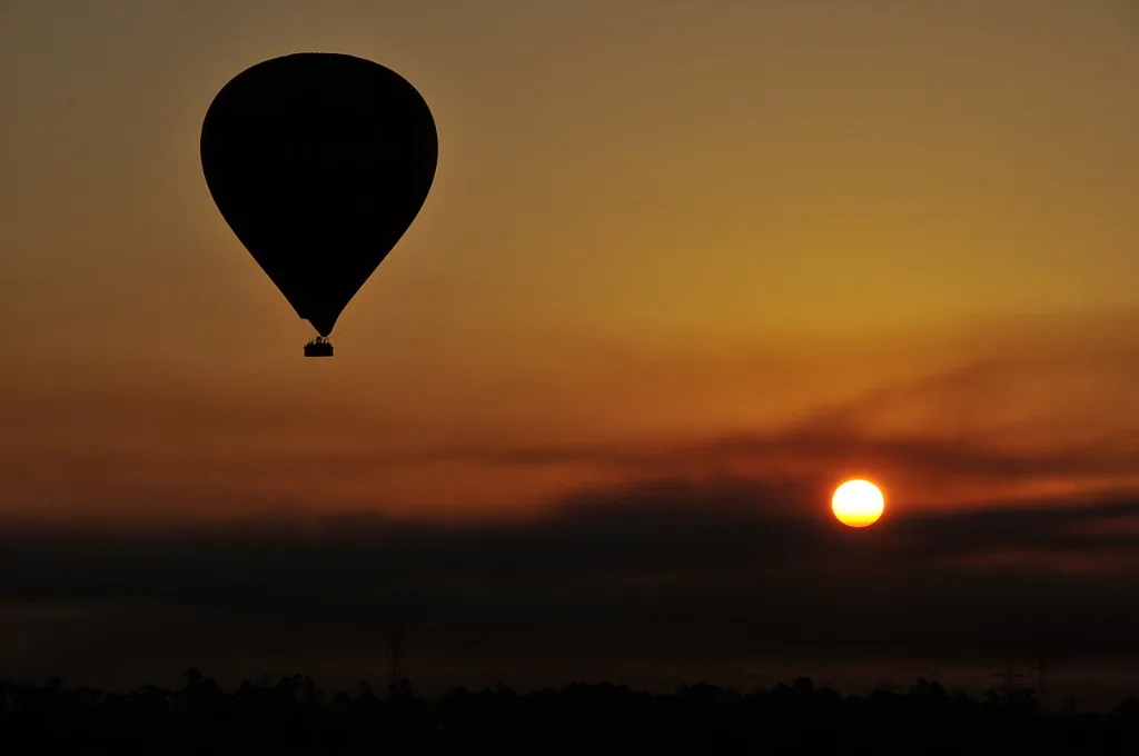 Hot air balloon tour in Luxor: a balloon rising against the pale dawn sky