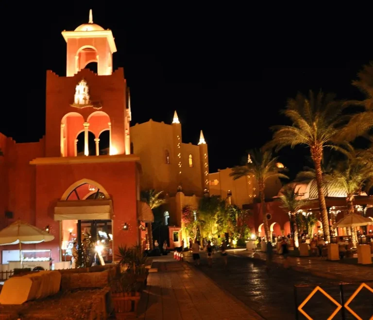 Red resort tower lit up at night among palms, a festive setting for Hurghada Christmas holidays