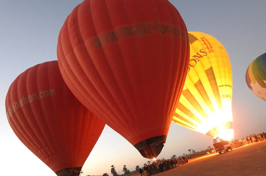 Hot air balloon Luxor price: balloons inflating on the West Bank launch field before sunrise