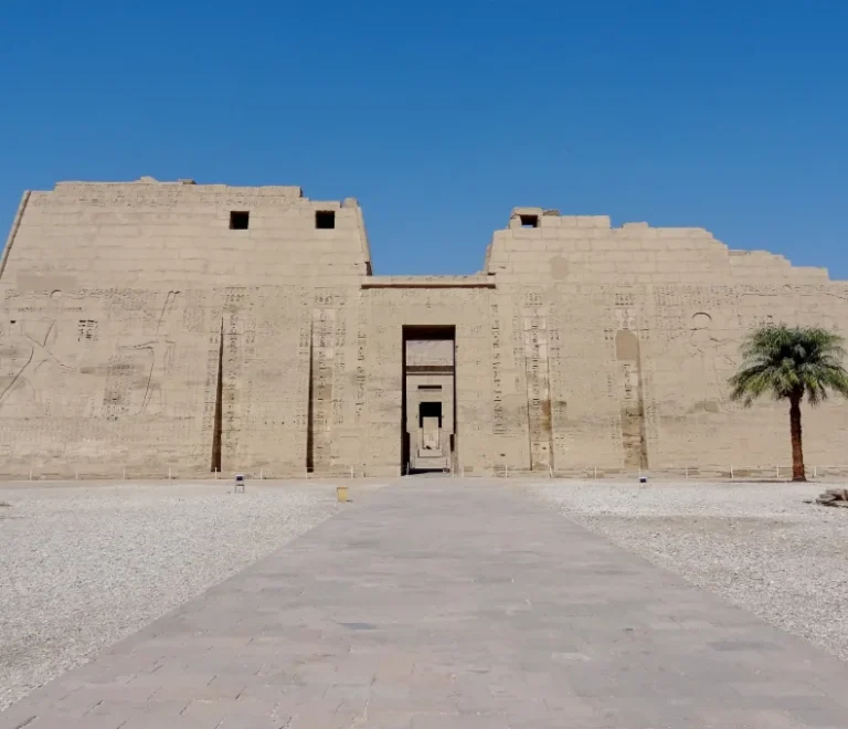 Medinet Habu: the towering first pylon of Ramesses III's temple beside a palm